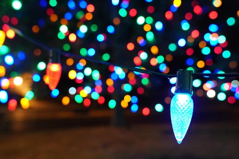 Close-up of red and blue C9 holiday bulbs with a blur of lights behind them